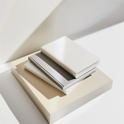 Two books stacked on a white surface with a light beige box underneath